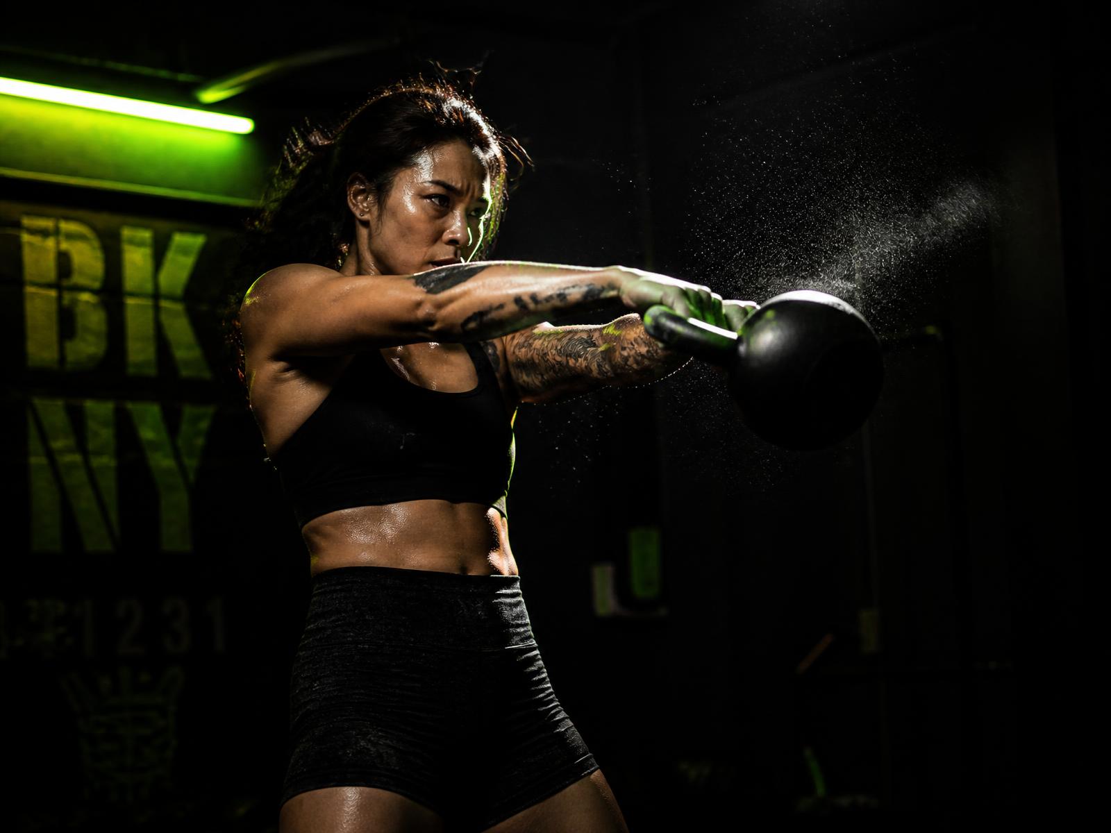 FKS athlete performing a kettlebell swing in a dark training studio